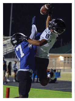 Two football players wearing black jerseys and holding hands. Description generated by AI