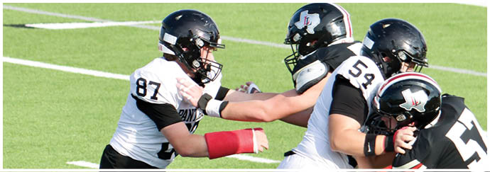 Three people wearing athletic clothing and cleats are engaged in a football play on a grassy field. Description generated by AI