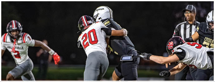 People in football uniforms are actively engaged in a game on a well-lit field at night. Description generated by AI