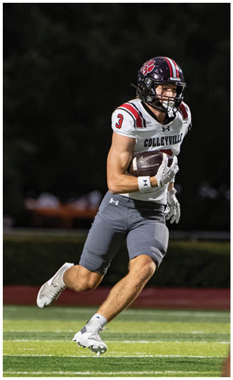 A person wearing a football uniform with a helmet is running on a field while holding a football. Description generated by AI