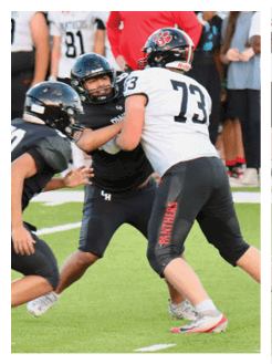 Two football players wearing black jerseys and holding hands. Description generated by AI
