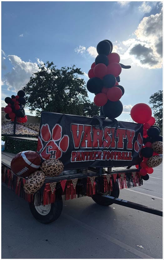 A close-up of a black banner with red and white text and a large red paw print design, partially obscured by leopard print fabric and red decorations. Description generated by AI