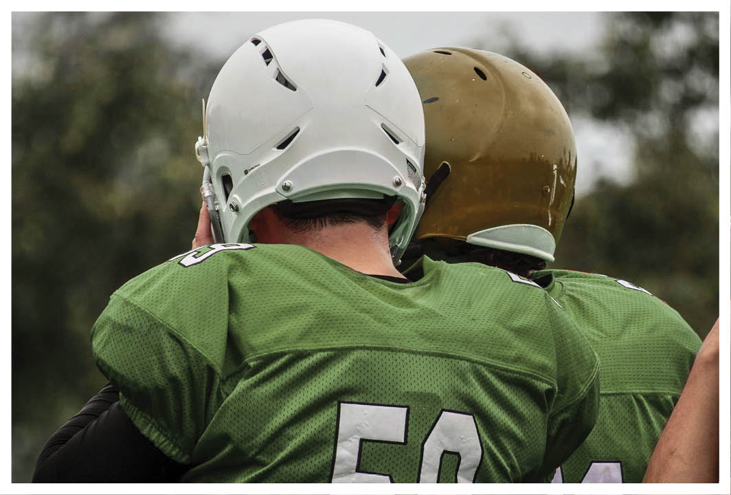 Two men wearing green jerseys. Description generated by AI