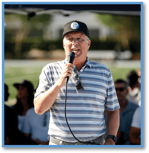 A man wearing a black shirt and headphones stands in front of a group of people. Description generated by AI
