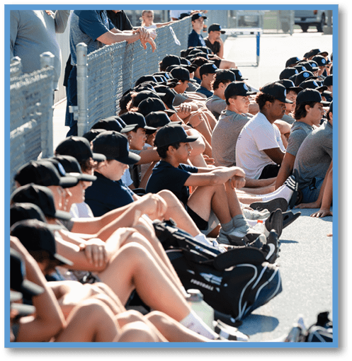 A man wearing a black shirt and headphones stands in front of a group of people. Description generated by AI