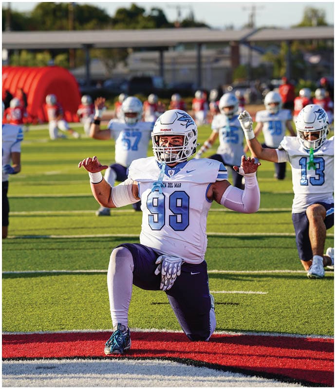 Three football players in blue and white uniforms running on a field. Description generated by AI