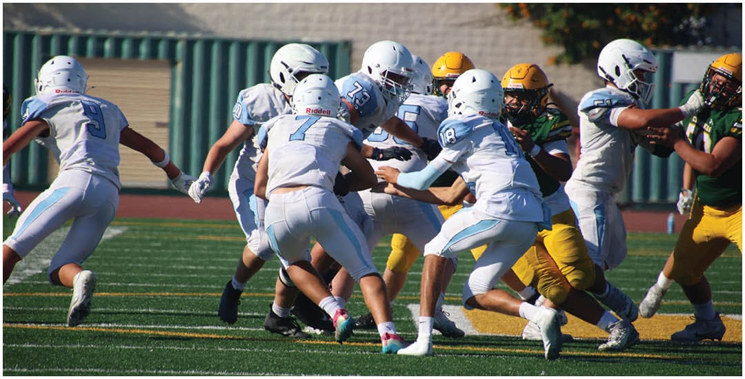 Three football players in blue and white uniforms running on a field. Description generated by AI