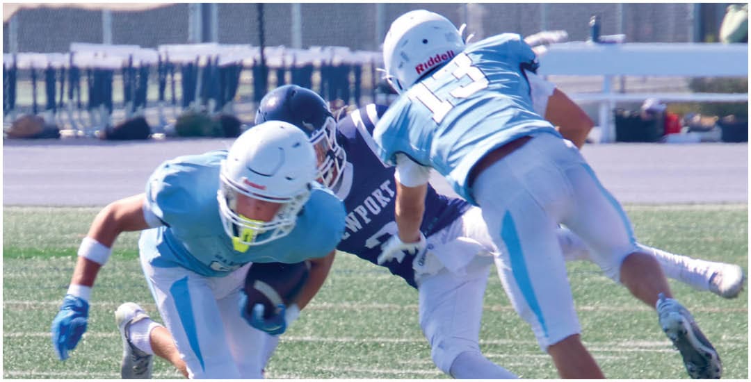 Three football players in blue and white uniforms running on a field. Description generated by AI