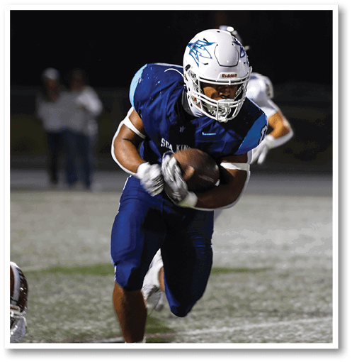 A football player wearing a black jersey with the number 6 on it. Description generated by AI