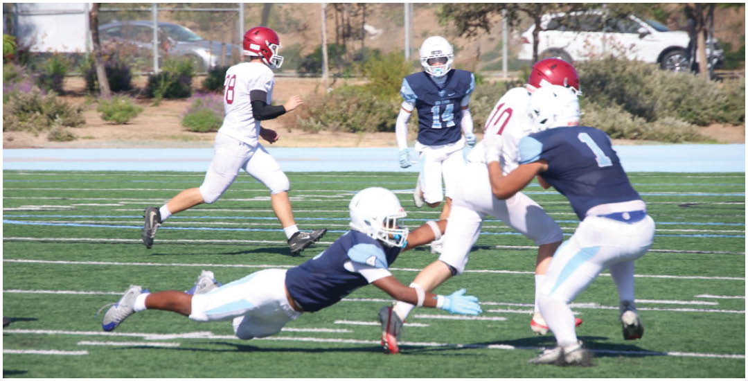 Three football players in blue and white uniforms running on a field. Description generated by AI