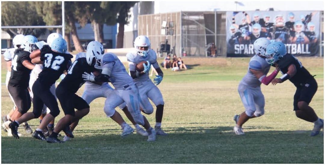 Three football players in blue and white uniforms running on a field. Description generated by AI