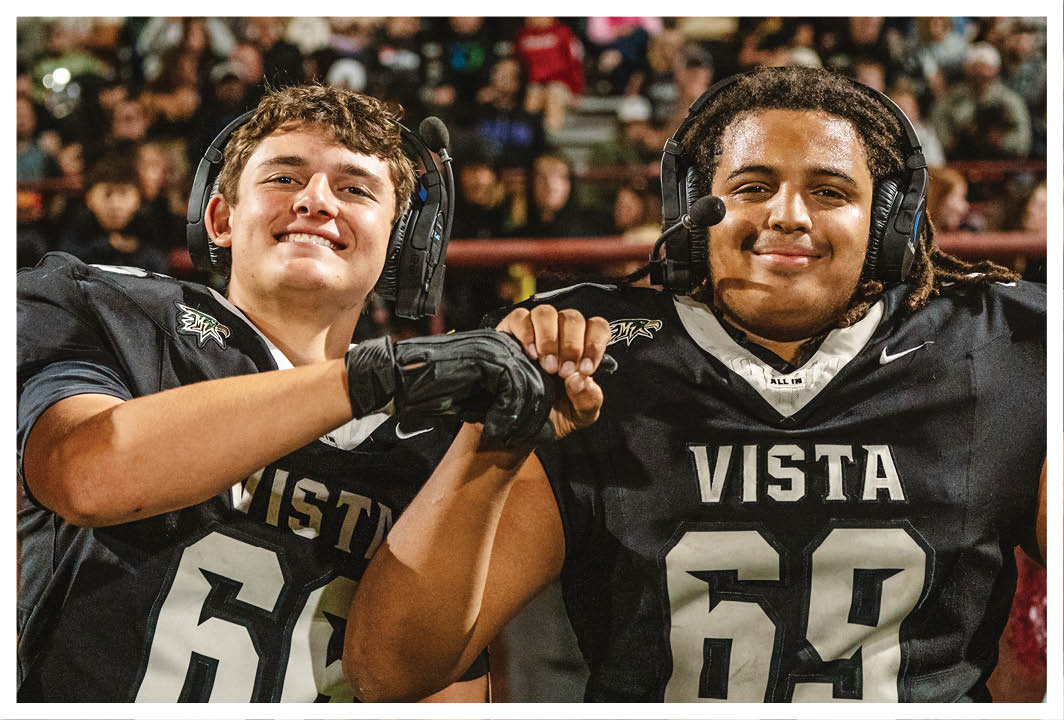 Two football players wearing black jerseys with the word Vista on them. Description generated by AI