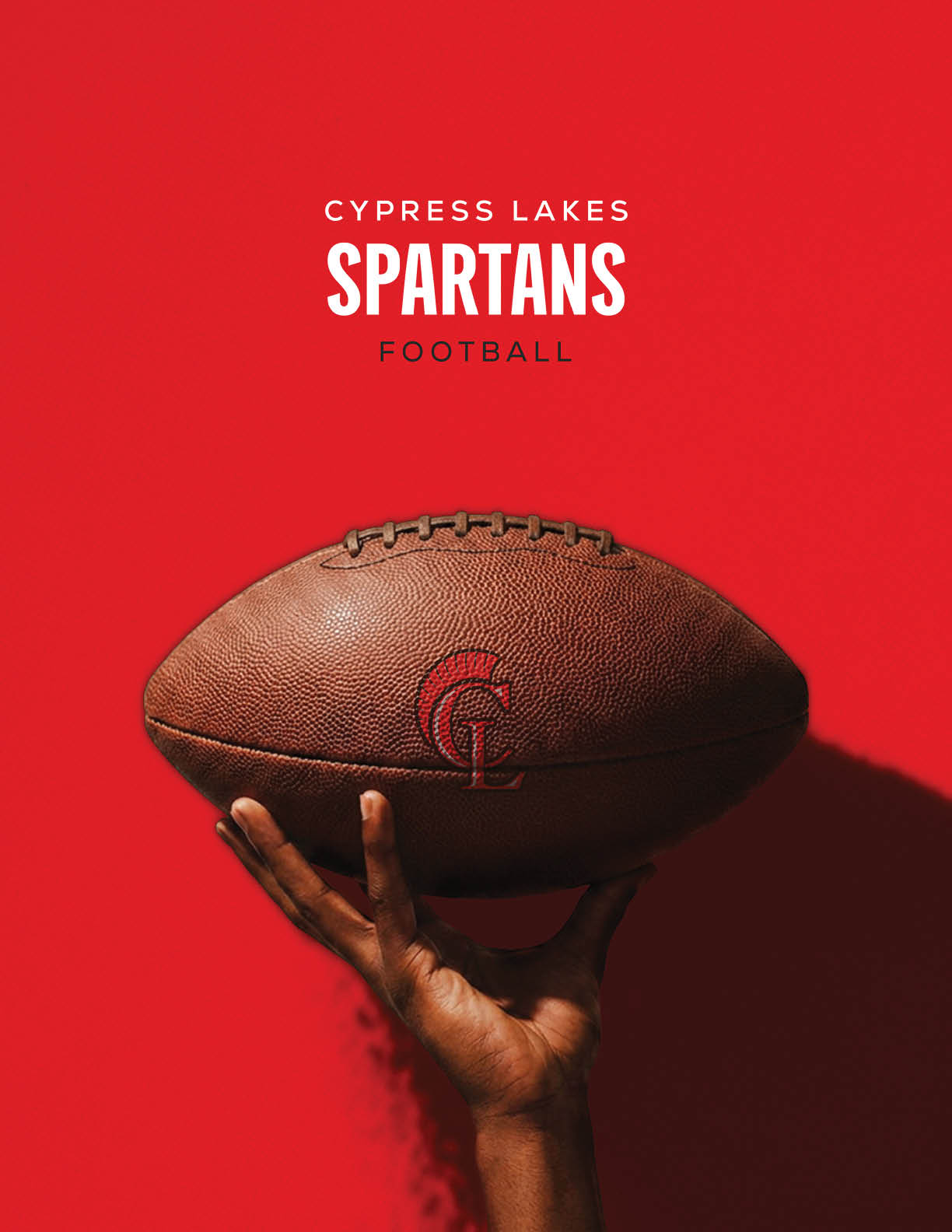 A hand is holding a brown football with a red “CL" logo against a bright red background with the text "Cypress Lakes Spartans Football" above it. Description generated by AI