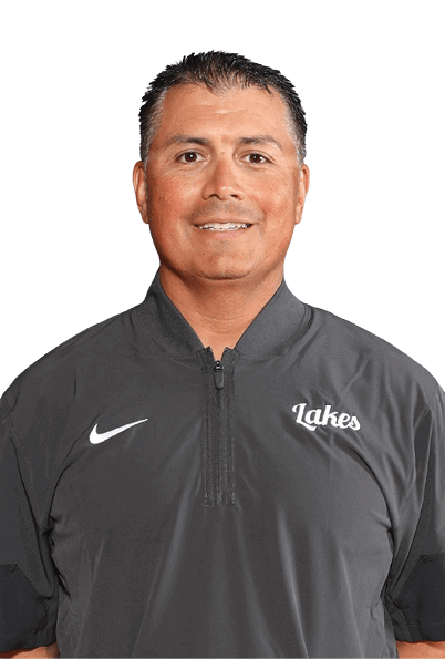 A person with short dark hair is wearing a dark gray Nike quarter-zip shirt with the word “Lakes" embroidered on the chest, smiling against a plain light background. Description generated by AI