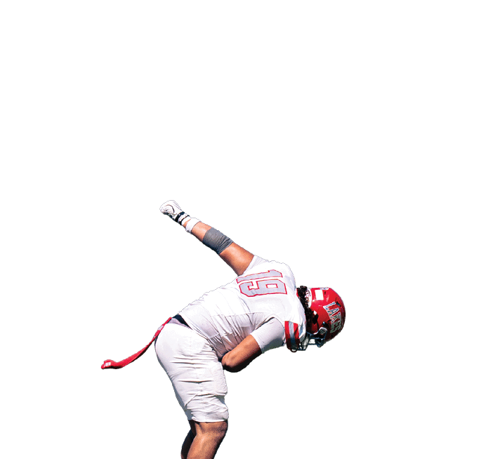 A person wearing a football uniform and helmet is bending forward on a grassy field with one arm extended backward. Description generated by AI