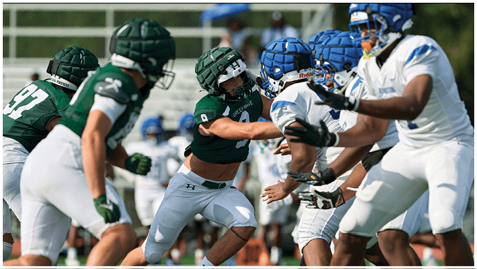 Three football players in blue and white uniforms running on a field. Description generated by AI