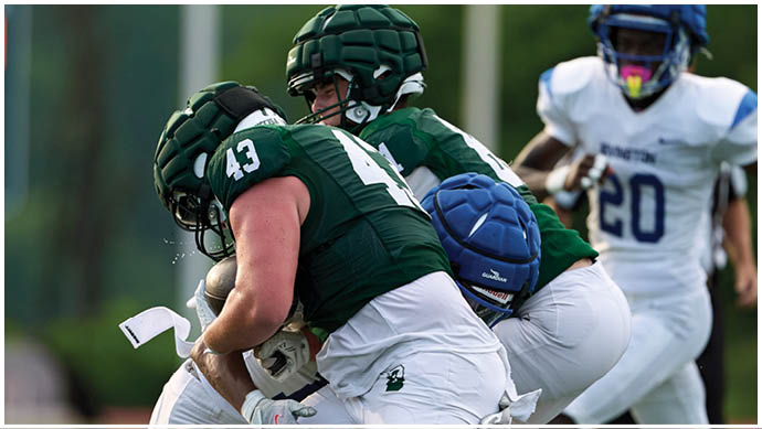 Three football players in blue and white uniforms running on a field. Description generated by AI