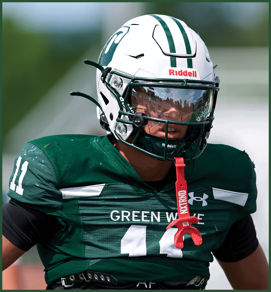 A football player in a green jersey is running with the ball. Description generated by AI