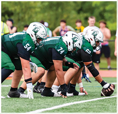 A football game is taking place with a group of men on the field. Description generated by AI
