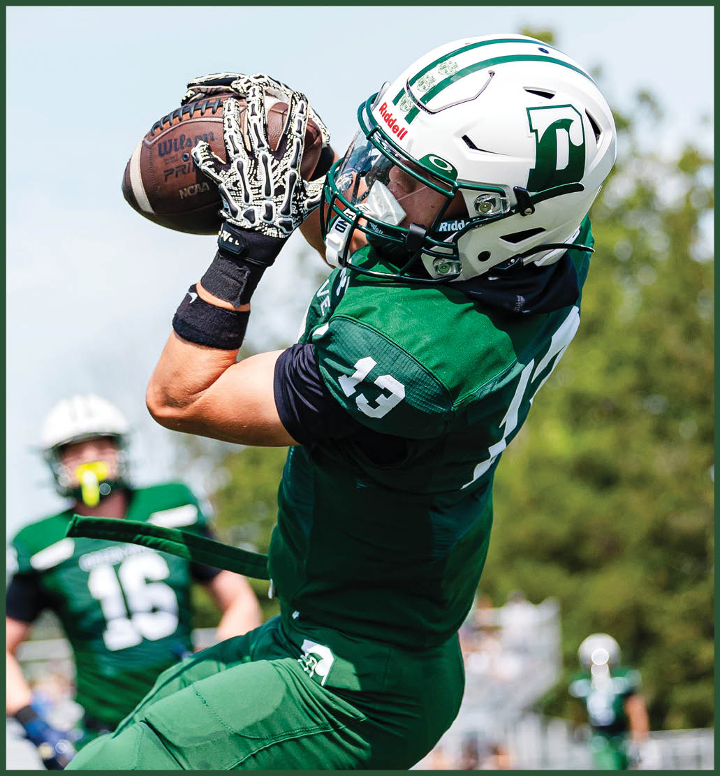 A football player in a green jersey is running with the ball. Description generated by AI