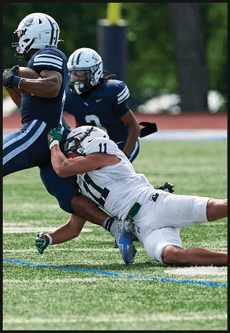 Two football players wearing blue and white uniforms. Description generated by AI