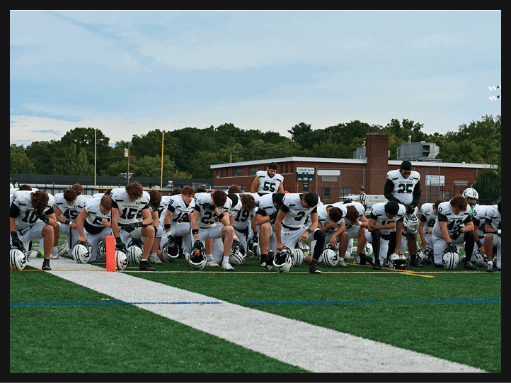 A group of football players on a field, one of them is running with a football. AI generated content