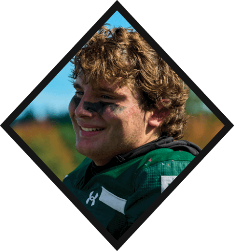 A football player wearing a black jersey with the number 10 sits on the ground with a football helmet on the ground next to him. AI generated content