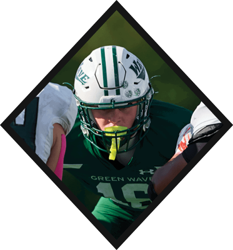 A football player wearing a black jersey with the number 10 sits on the ground with a football helmet on the ground next to him. AI generated content