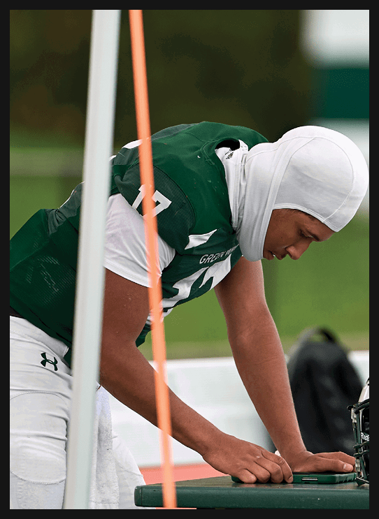 A football player wearing a helmet and white uniform is holding his helmet above his head. AI generated content