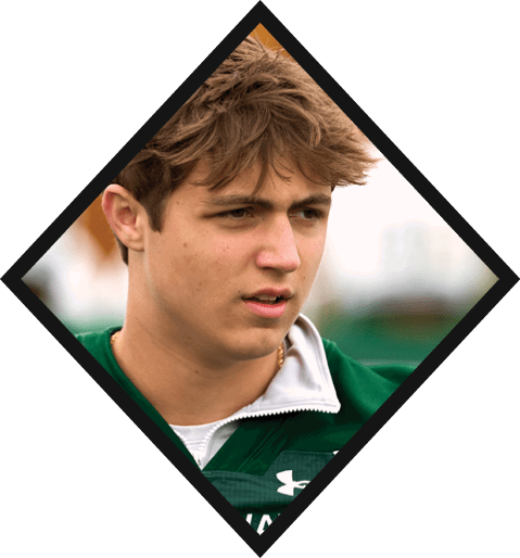 A football player wearing a black jersey with the number 10 sits on the ground with a football helmet on the ground next to him. AI generated content