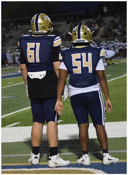 Two football players stand on the field, one with the number 60 on his jersey. AI generated content