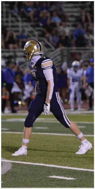 A football player in a blue uniform is running on the field. AI generated content