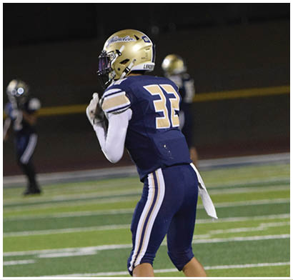 A football player wearing a blue and white uniform is holding a football in his hands. AI generated content