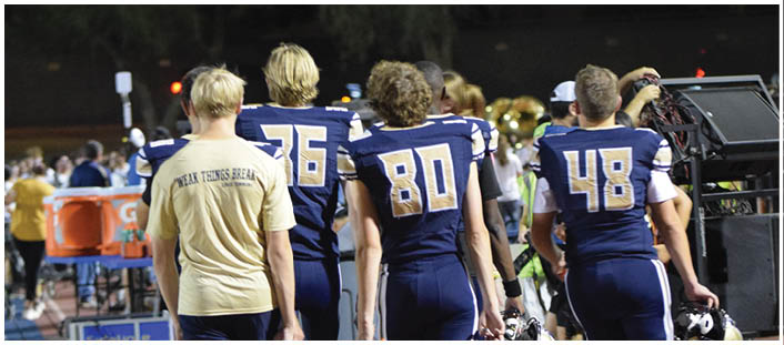A group of people wearing blue and gold uniforms are walking on a track. AI generated content