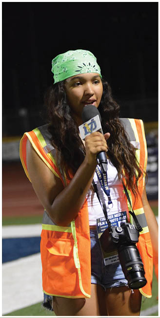 A woman in an orange vest is holding a microphone and talking into it. AI generated content