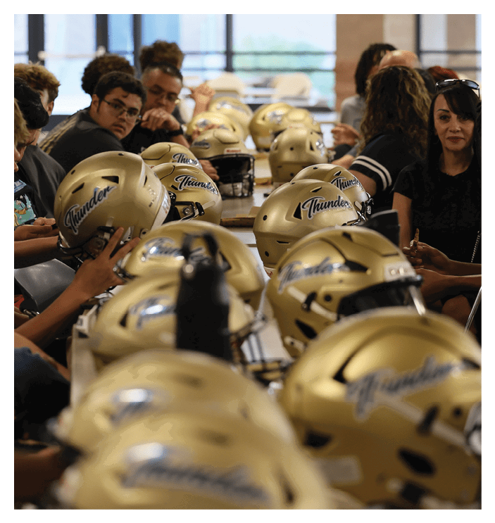 A group of people are sitting around a table with football helmets on it. AI generated content