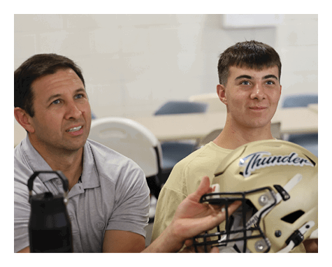Two men are holding a football helmet. AI generated content