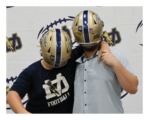 Two men wearing football helmets pose for a picture. AI generated content