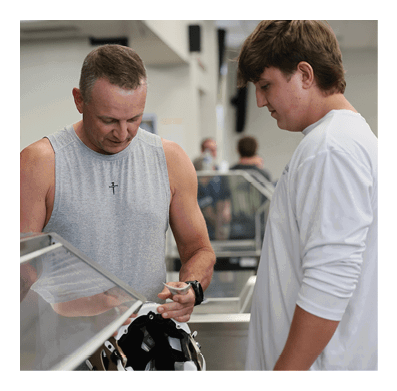 Two men are looking at a football helmet. AI generated content