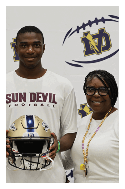 A man and a woman are standing in front of a backdrop. The man is holding a football helmet. AI generated content