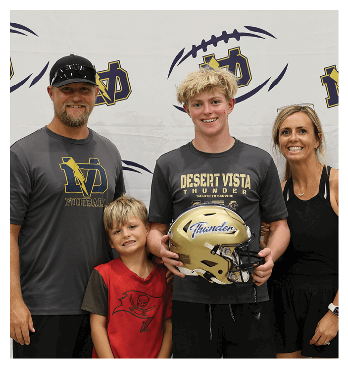 A man, woman, and two children pose for a photo with a football helmet. AI generated content
