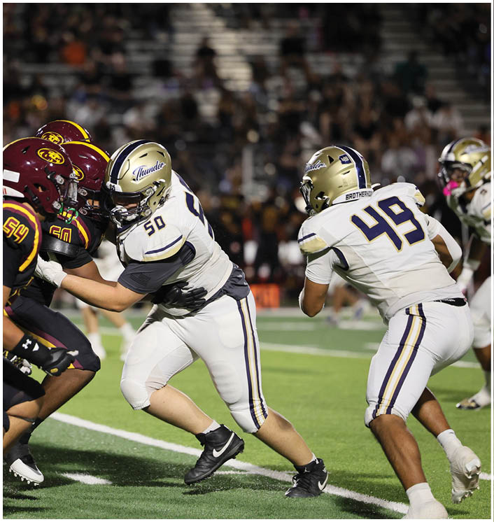 People wearing sports uniforms are engaged in a close-up action scene on a football field. Description generated by AI