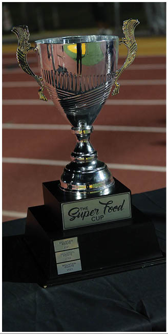 A shiny silver trophy with a black base displaying a plaque that reads “The Super Food Cup." Description generated by AI
