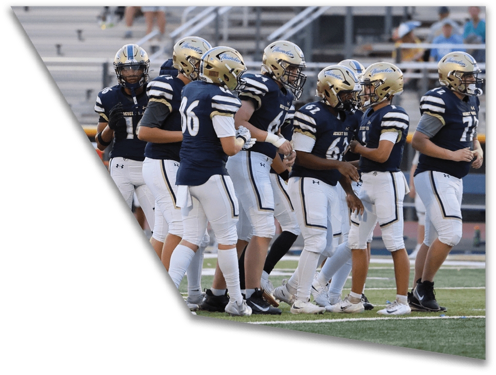 A group of people wearing football uniforms and helmets are standing together on a field with bleachers in the background. Description generated by AI