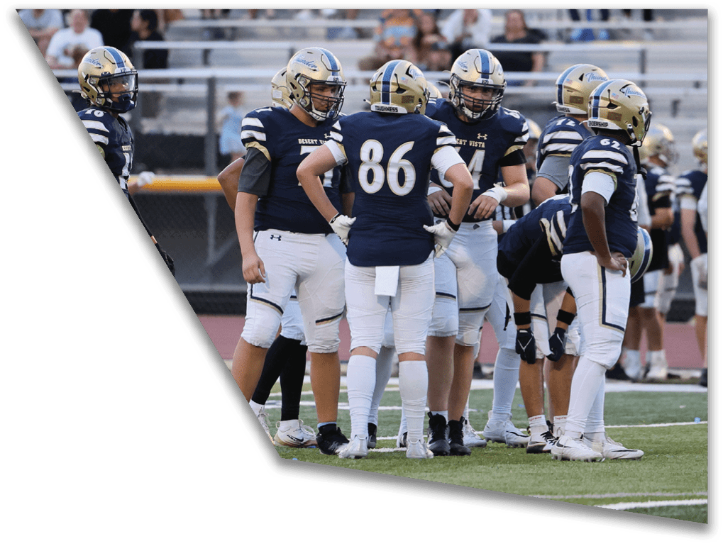 A group of people wearing navy blue and white football uniforms are standing together on a football field. Description generated by AI