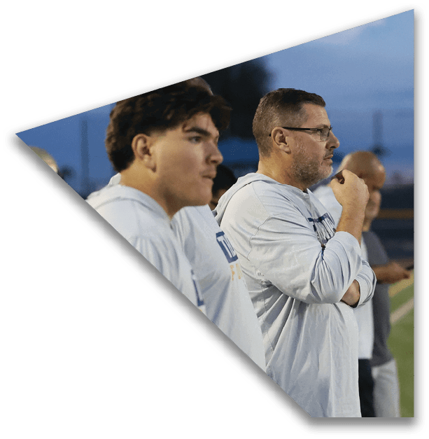 Several people wearing light-colored long-sleeve shirts stand closely together outdoors, appearing focused and attentive during an evening event. Description generated by AI