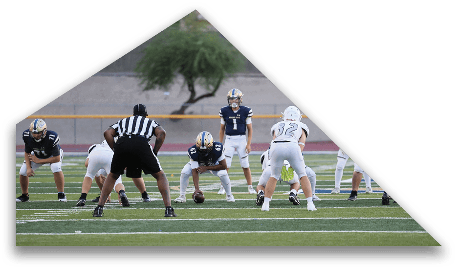 A group of people in football uniforms are positioned on a field preparing for a play during a game. Description generated by AI