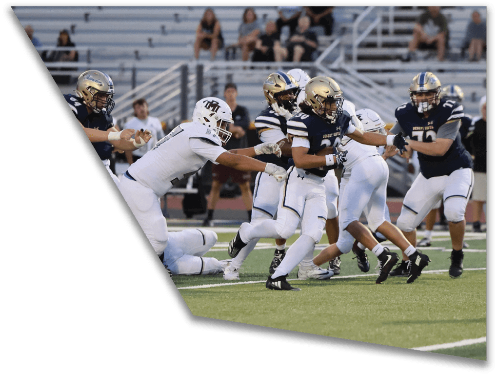 People in football uniforms are actively engaged in a play on a field with bleachers and spectators in the background. Description generated by AI