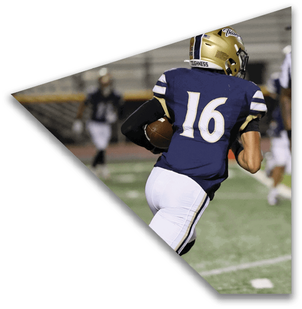 A person wearing a dark blue sports jersey with the number 16 and white pants is running on a football field while holding a football, with a referee standing nearby. Description generated by AI
