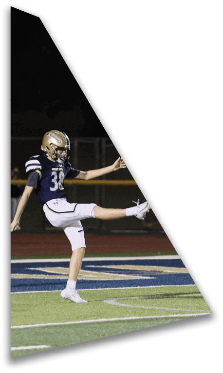 A person wearing a dark sports jersey and white pants is standing on a green football field near the end zone. Description generated by AI